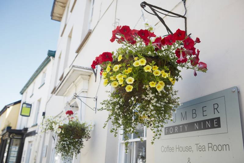 Image of lovely hanging baskets outside one of Usks local coffee shops. ©  Visit Monmouthshire